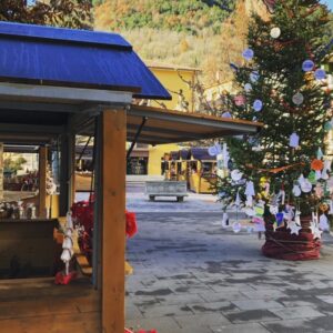 Una caseta de fusta amb parada nadalenca i un arbre de Nadal engalanat, a la plaça del mercat de Ribes